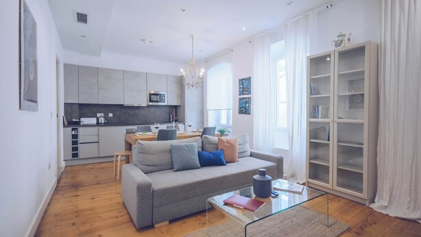 A modern living room with a grey sofa, a glass coffee table, and a wooden floor. - Spacious cozy 2BR/2BA in the city center (Gibraltar)
