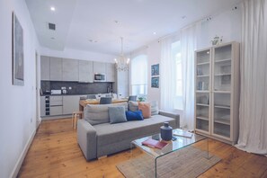 Un salon moderne avec un canapé gris, une table basse en verre et un plancher en bois.