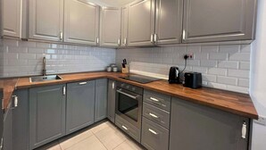 Una cocina moderna con armarios grises, encimera de madera, horno empotrado y cafetera.