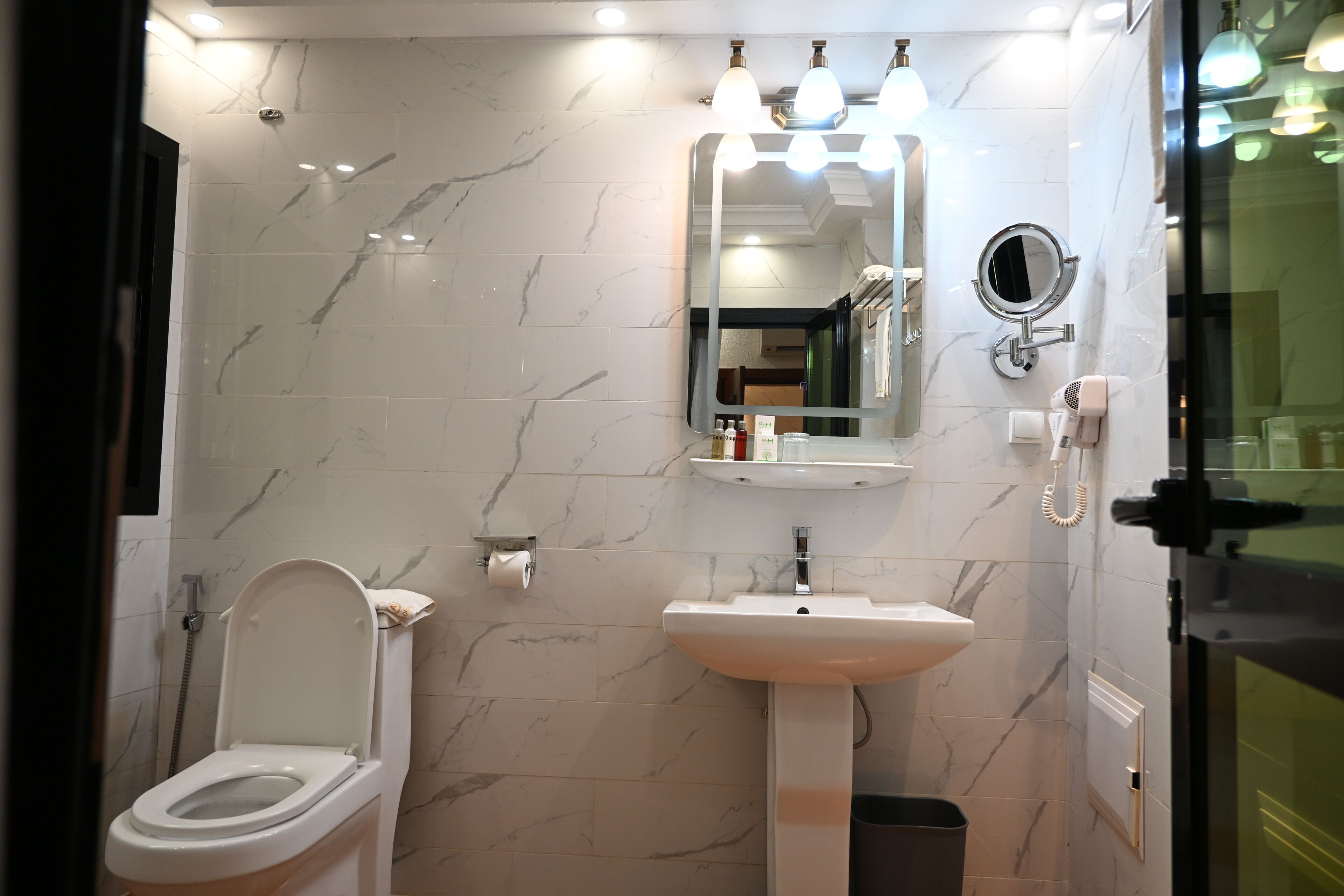 A bathroom with a toilet, sink, mirror, and towel rack.