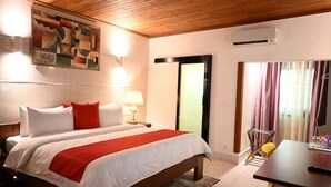 Una habitación de hotel con cama, una mesa, una lámpara y un equipo de aire acondicionado.
