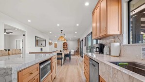 A modern kitchen with wooden cabinets, marble countertops, and a central island. - When in Glen | Panoramic View | Pool / Hot Tub (Glen Ellen)