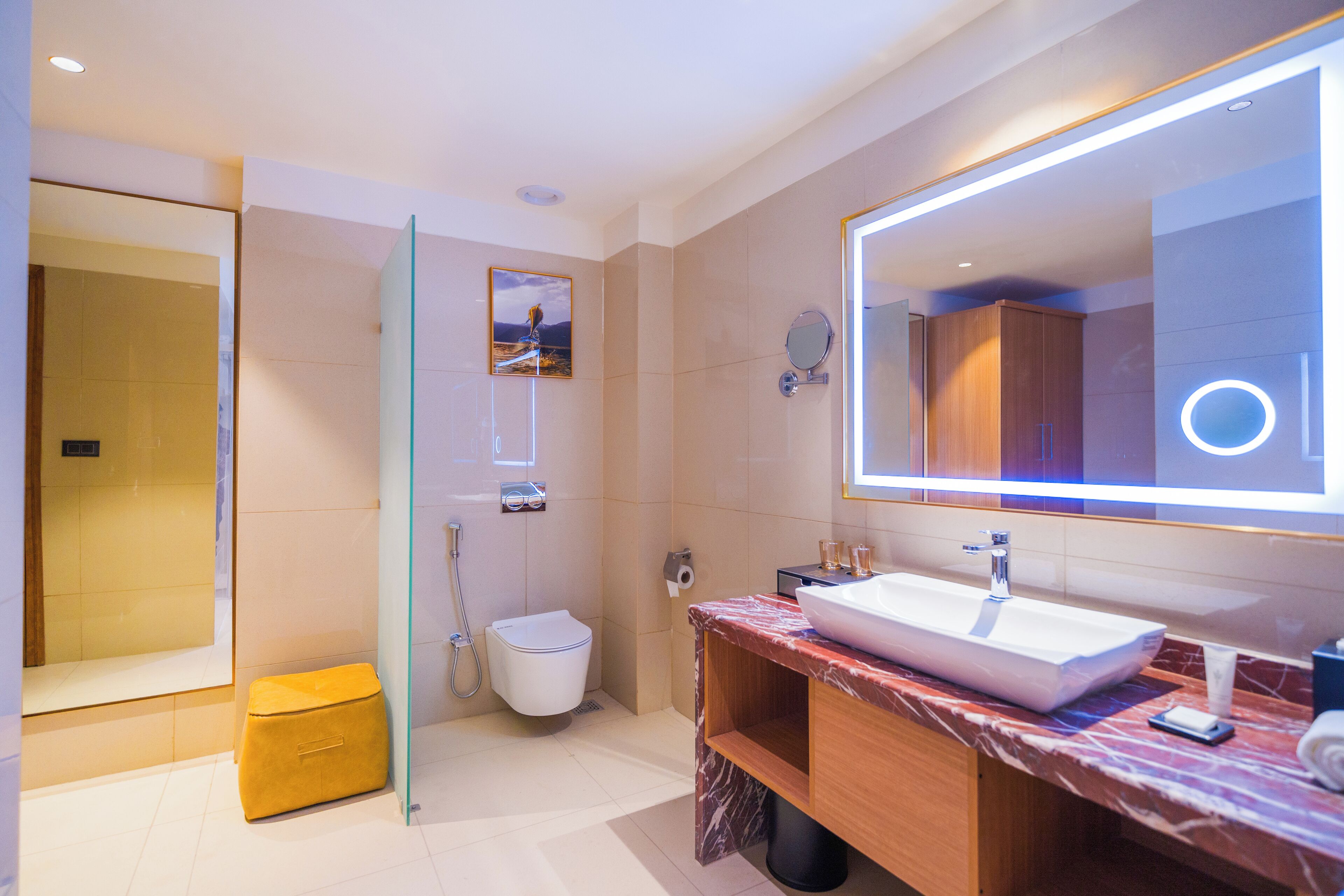 A modern bathroom with a glass shower enclosure, a white toilet, a marble vanity with a large mirror, and a sink.