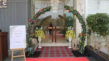 A reception area with a red carpet, a welcome sign, and a floral archway.