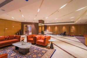 A spacious lobby with a modern design, featuring a seating area with orange sofas, a marble coffee table, and a patterned rug. - The Maple Hotel-Bhopal (Bhopal)