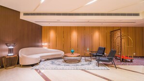 A modern hotel lobby with a curved sofa, a round coffee table, and two chairs.