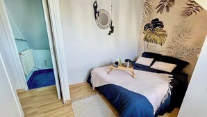 A bedroom with a bed, a bedside table, a hanging light fixture, and a wall with a floral mural.