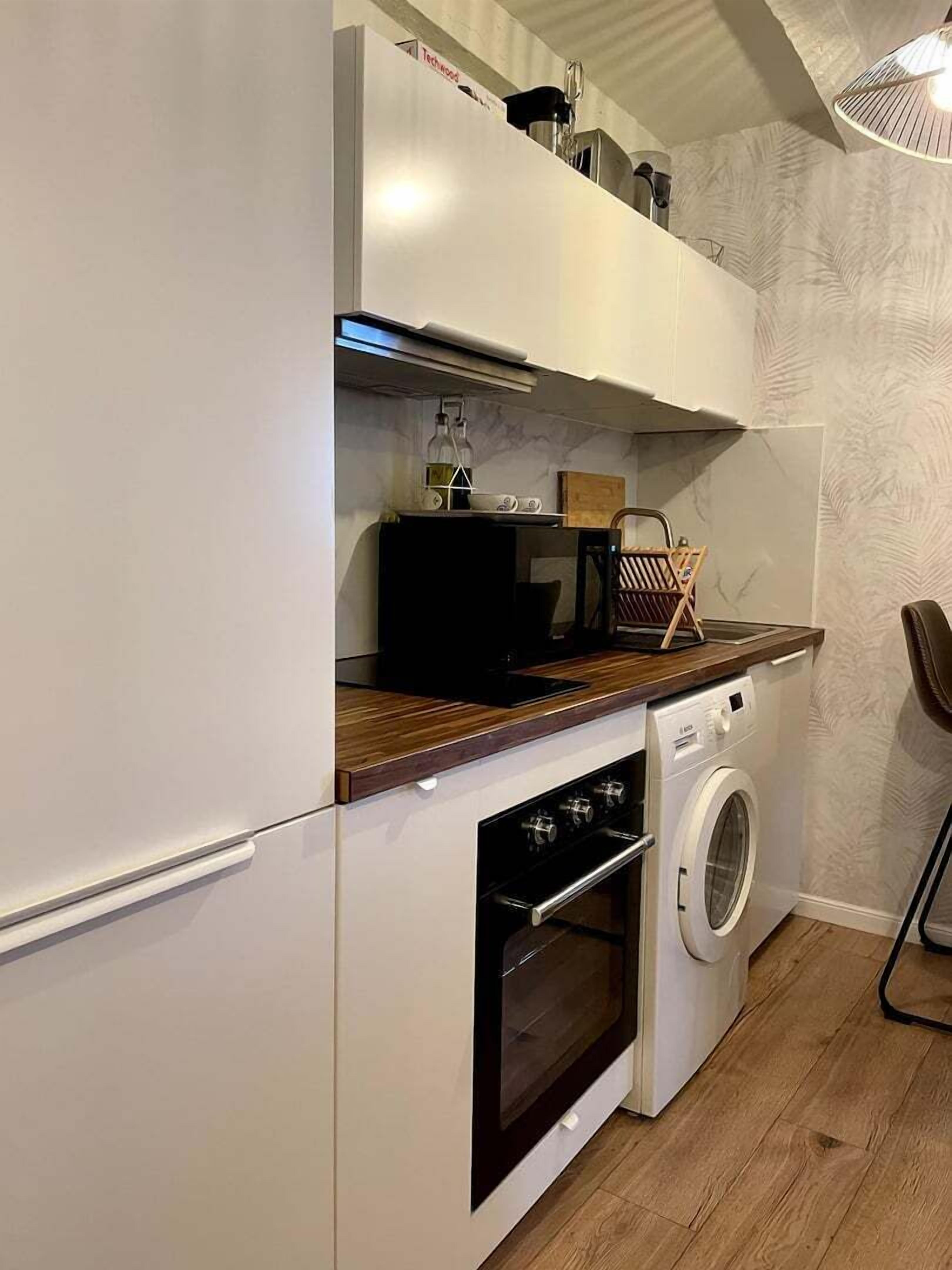 Eine kompakte Küche mit Backofen, Waschmaschine und Mikrowelle.