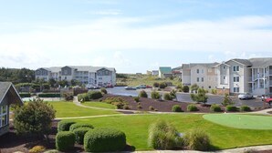 Una zona residencial con edificios de apartamentos de varios pisos, un estacionamiento y un césped bien cuidado con un campo de golf.