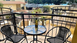 Ein Balkon mit rundem Tisch, zwei Stühlen, einer Flasche und zwei Weingläsern.
