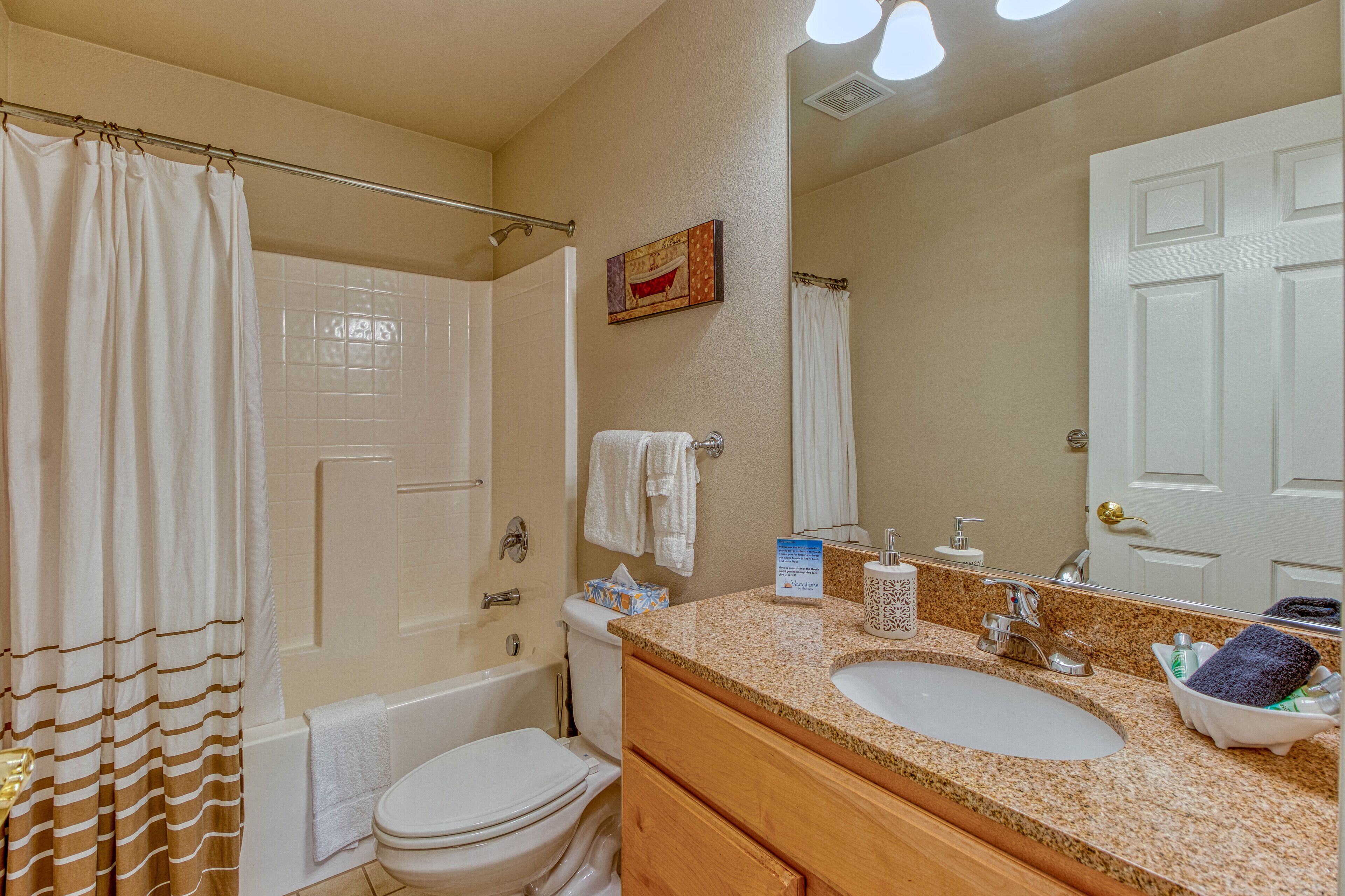 A bathroom with a bathtub, toilet, sink, and a large mirror.
