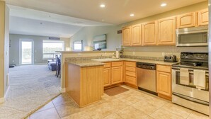 A modern kitchen with wooden cabinets, a granite countertop, stainless steel appliances, and a view to the dining area.