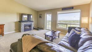 A living room with a stone fireplace, a large window with a view, a leather couch, and a coffee table.