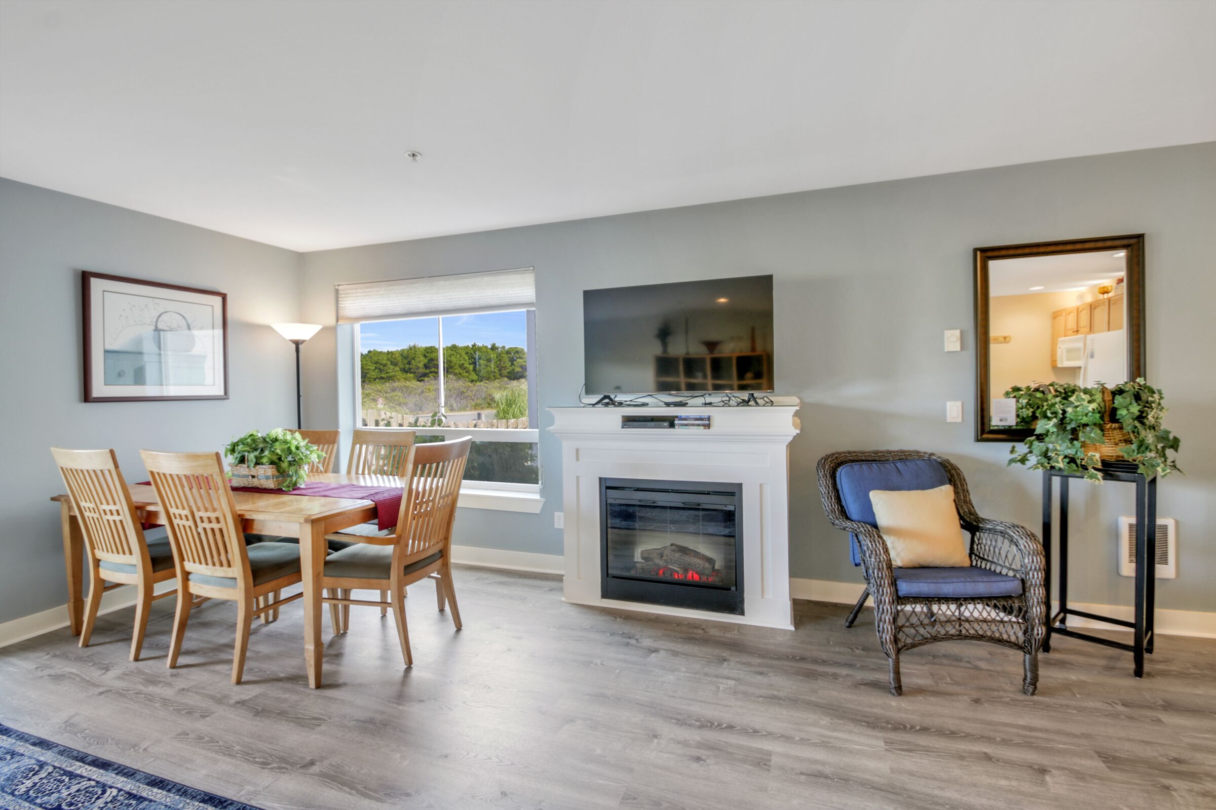 A dining area with a fireplace, wooden chairs, and a table with a plant.