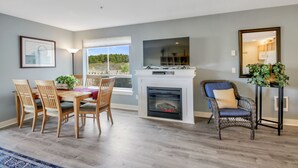 Un coin repas avec une cheminée, des chaises en bois et une table agrémentée d’une plante.