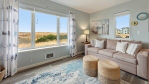 A room with a large window, a beige sofa, a blue rug, and a lamp. - 113 - A Breath of Fresh Air, Dogs welcome! (Westport)