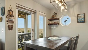 A dining area with a table and chairs, a hanging light fixture, and wall decorations including a bird and a sign with a message. - 113 - A Breath of Fresh Air, Dogs welcome! (Westport)