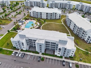 Un immeuble résidentiel moderne à plusieurs étages, doté d’une cour intérieure, d’un parking et d’une piscine.
