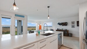 A modern kitchen with a large island, white cabinetry, and a view of the outdoors. - 613 - A paw-some place for rest, relaxation, and Ball! (Westport)