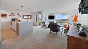 A spacious living area with a kitchen, a dining area, and a large window offering a view of the outdoors. - 613 - A paw-some place for rest, relaxation, and Ball! (Westport)