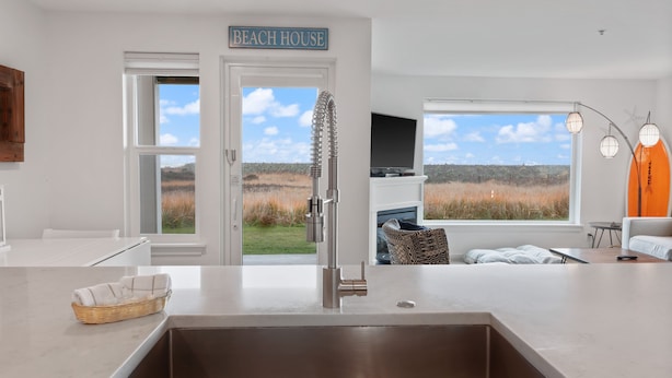 A modern kitchen with a large window, a sign reading "BEACH HOUSE," and a view of the outdoors. - 613 - A paw-some place for rest, relaxation, and Ball! (Westport)