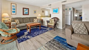 Un salon avec un canapé, un fauteuil à bascule, une table basse et un tapis.