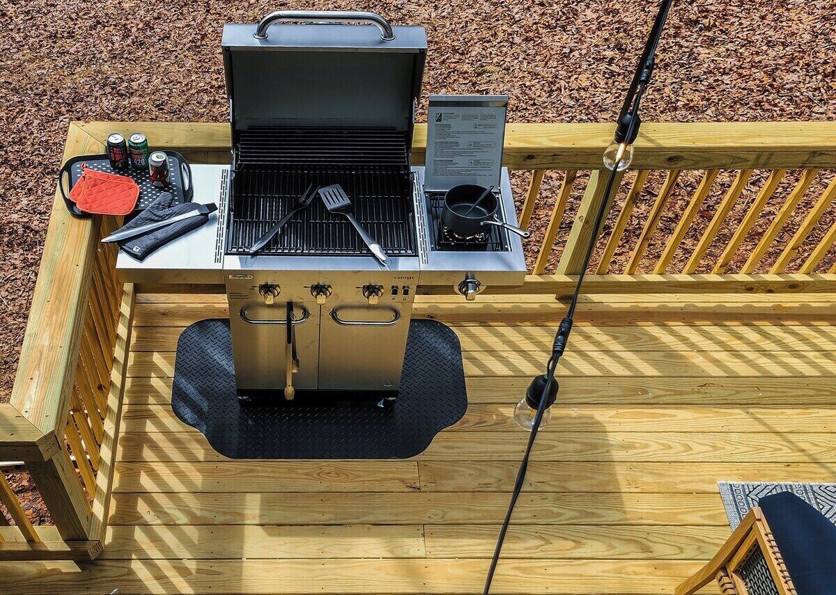 Ein Grill mit integriertem Räucherofen, ein tragbarer Grill und ein Topf auf einer Holzterrasse.