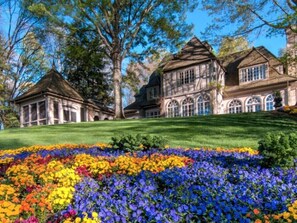 A large, historic building with multiple sections, surrounded by a well-maintained lawn and colorful flower beds. - View from the Canoe | Resort Access, Views & Games (Jasper)