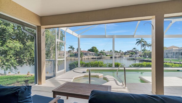 A sunlit patio with a pool, outdoor seating, and a view of a lake and surrounding neighborhood. - The Seahorse House I Wide Views on Tip Lot Minutes from the Gulf (Marco Island)