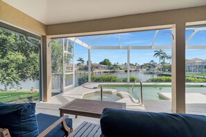Eine sonnige Terrasse mit Pool, Sitzgelegenheiten im Freien und Blick auf einen See sowie die umliegende Wohngegend.