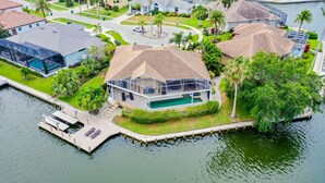 A waterfront property with a large house, a dock, and a swimming pool. - The Seahorse House I Wide Views on Tip Lot Minutes from the Gulf (Marco Island)