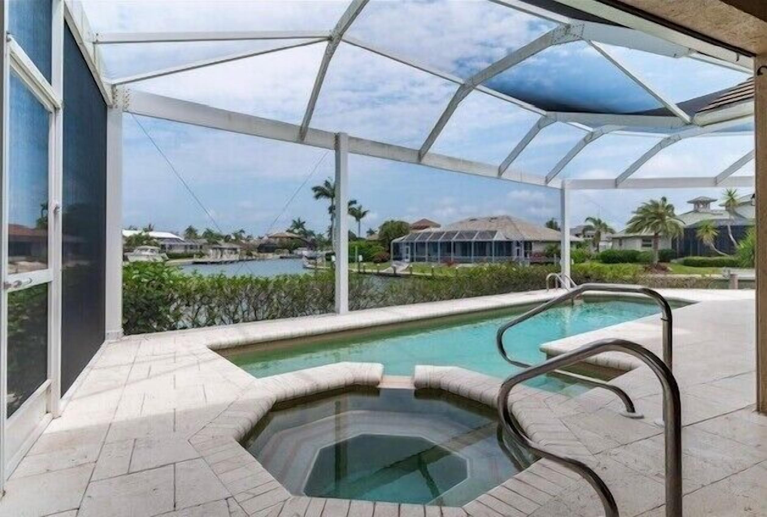 A covered outdoor swimming pool with a hot tub and a view of a residential area.