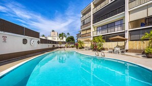 A swimming pool with a no swimming sign, surrounded by a building with balconies and outdoor seating.