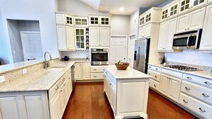 A kitchen with white cabinetry, a granite countertop, a built-in oven, and a microwave.