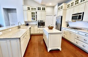 A kitchen with white cabinetry, a granite countertop, a built-in oven, and a microwave.