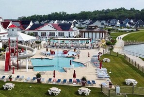 A resort with a large swimming pool, a water slide, and a covered area with lounge chairs and umbrellas.