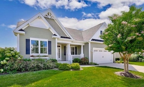 A two-story house with a front porch, a garage, and a well-maintained lawn.