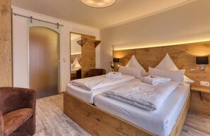 A double bed with white linens, a wooden headboard, and a nightstand with a lamp. - Hotel Waldfrieden (Spiegelau)
