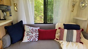 A cozy living room with a grey sofa, a white throw blanket, and colorful pillows. - Cozy motorhome with loads of outdoor activities, farm animals and trails (Stockbridge)