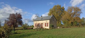 A two-story house with a sloped roof, a chimney, and a small porch with red shutters. - Gite Rural Entièrement Rénové, Près du Canal du Nivernais Avec Très Belle vue (saint gratien savigny)
