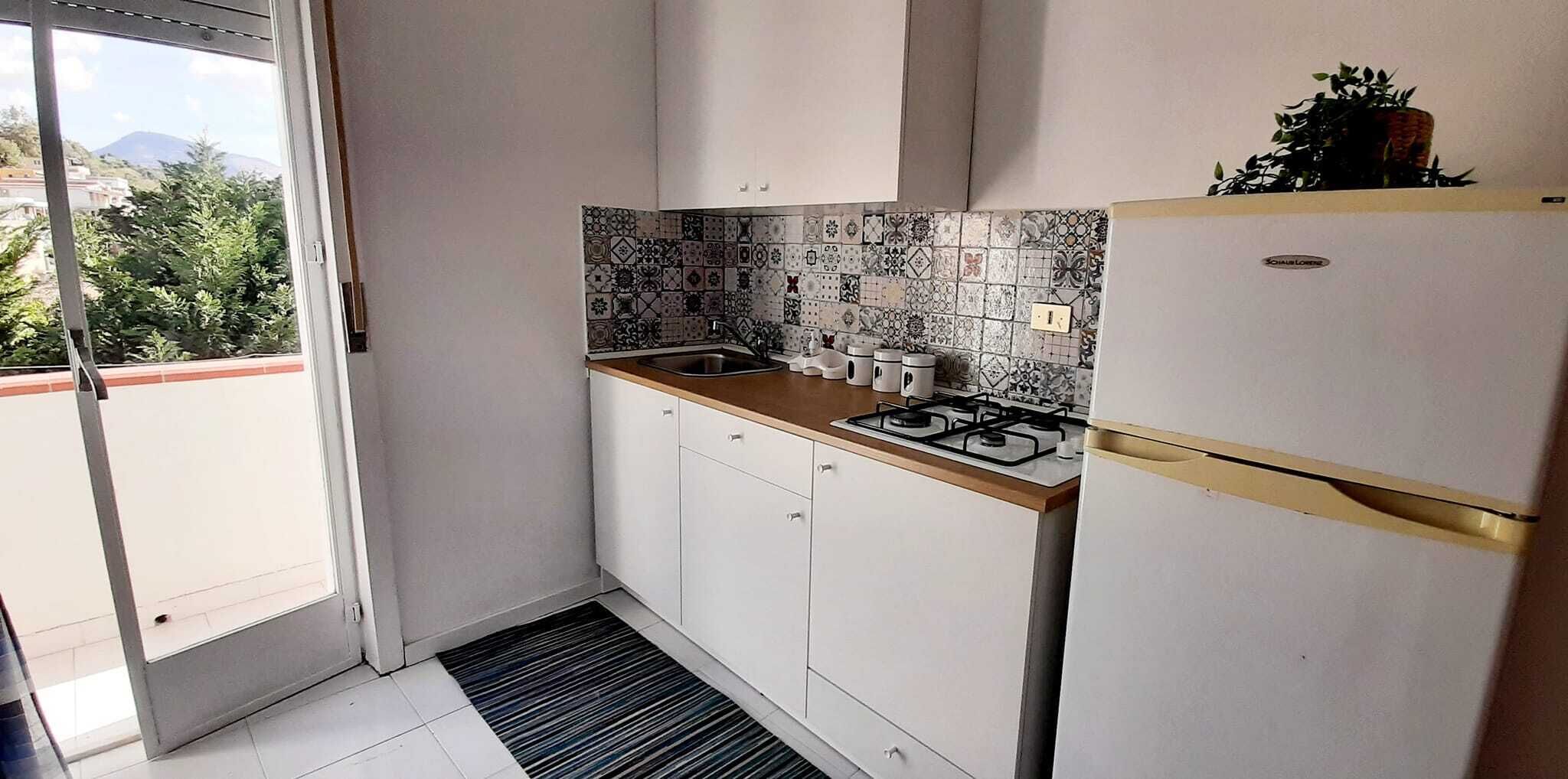 A compact kitchen with white cabinets, a gas stove, and a refrigerator.