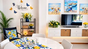 Un espace repas moderne avec une table ronde, des chaises, un téléviseur et des œuvres d’art décoratives au mur.