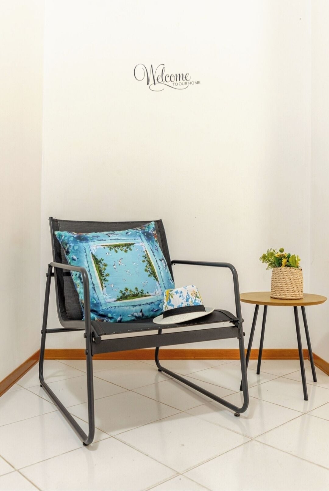 A black metal chair with a blue cushion and a small table with a woven basket and a plant.