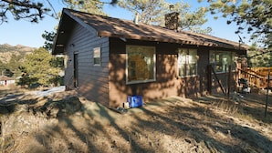 A small, single-story cabin with a sloped roof, large windows, and a chimney.