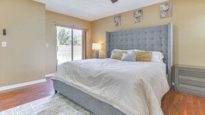 Une chambre avec un grand lit, un ventilateur de plafond et des œuvres d’art accrochées aux murs.