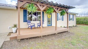 A covered porch with two chairs, a welcome sign, and a potted plant.