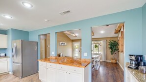 A modern kitchen with a large island, white cabinets, and a stainless steel refrigerator.