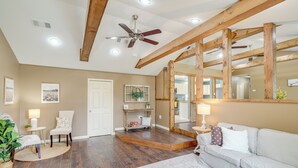 A spacious living room with hardwood flooring, a ceiling fan, a large mirror, and a light-colored sofa.