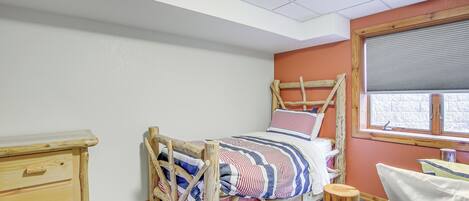 Ein Schlafzimmer mit einem hölzernen Bett, einer Kommode, einem Fenster mit Jalousien und einem gefliesten Boden.