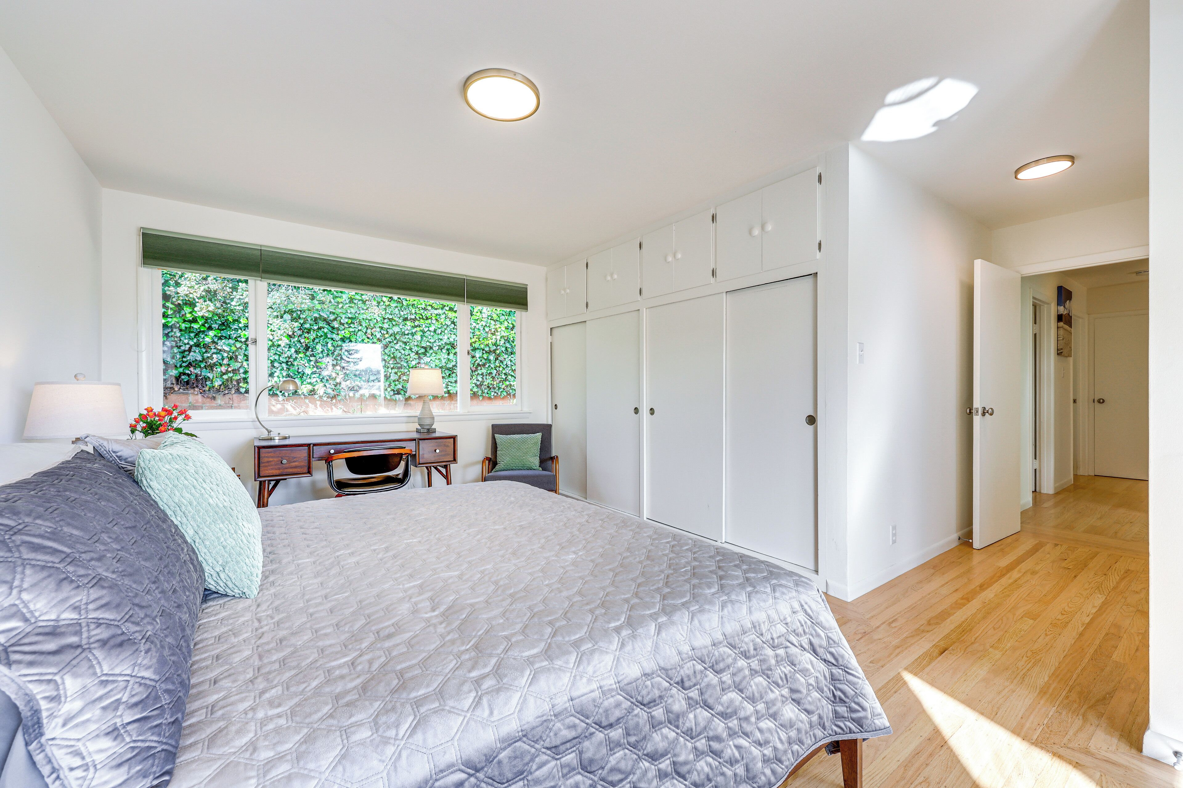 A bedroom with a large bed, a desk, and a wardrobe.